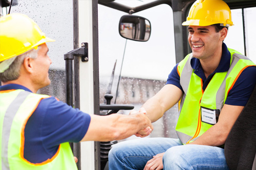 Operarios saludándose con cascos puestos para trabajar