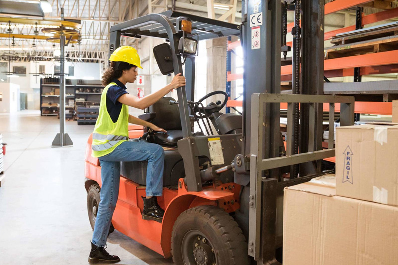 trabajadora subiendo a caretilla elevadora para empezar su turno de trabajo.
